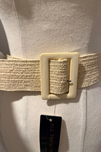 Mannequin wearing a beige belt with a square buckle on a plain background