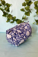 Floral boho patterned fabric box on a light surface with green leaves in the background