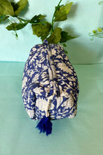 Blue and white boho patterned fabric pouch with tassel on a light green background