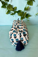 Decorative fabric pouch with boho floral pattern and tassel on a light blue background