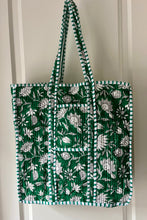 Green tote bag with boho floral pattern hanging on a white door