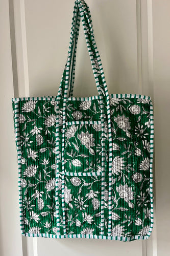 Green tote bag with boho floral pattern hanging on a white door