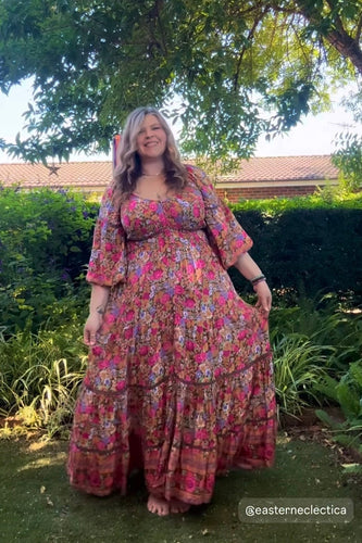 Woman wearing a boho floral dress standing outdoors with greenery in the background