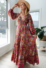 Woman wearing a colorful boho floral dress and wide-brimmed hat indoors.