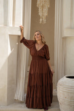 Woman in a boho brown dress standing in a decorative interior setting