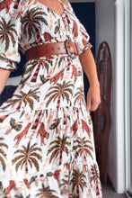 Woman wearing a boho patterned dress with a belt in an indoor setting