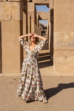 Woman in a  boho floral dress standing in front of ancient Egyptian temple architecture.