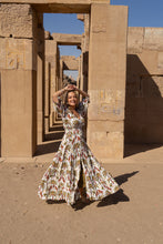Woman in a boho floral dress standing in front of ancient Egyptian temple architecture.