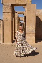 Woman in a boho floral dress standing in front of ancient temple architecture.