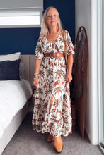 Woman in a boho patterned dress standing in a bedroom.