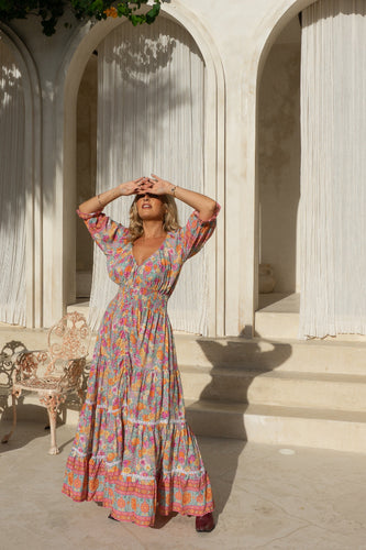 Woman in a colorful boho dress standing in front of classical architecture