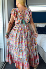 Woman wearing a colorful boho floral dress in a bedroom setting