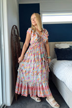 Woman in a boho floral dress standing in a bedroom.