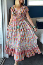 Woman wearing a colorful boho floral dress in a bedroom setting