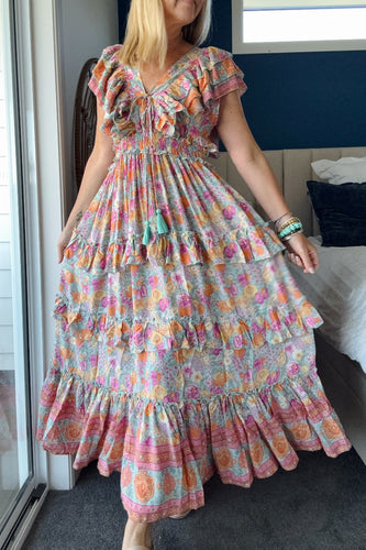Woman wearing a colorful boho floral dress in a bedroom setting