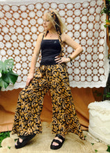 A woman wearing a yellow boho patterned outfit in a modern indoor setting in a side view position.