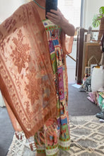 Person wearing a boho patterned outfit with a colorful design, standing in a room with furniture and decor.