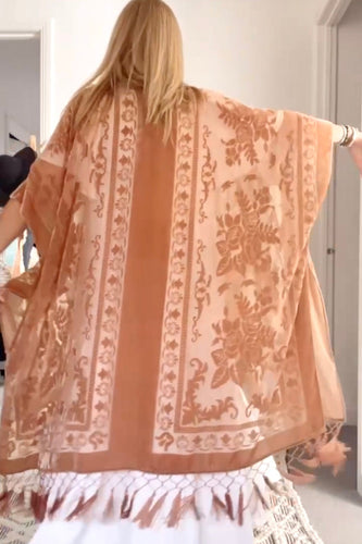 Person wearing a boho peach-colored scarf with intricate patterns in a room.