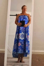 Woman wearing a blue floral boho dress standing in front of a mirror.