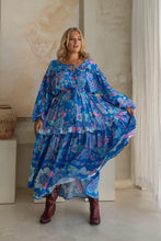 Woman wearing a blue boho floral dress in an indoor setting
