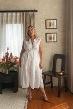 Woman in a white dress standing in a room with decor elements.
