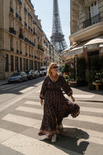 A woman in a floral boho dress standing in the Eiffel Tower in the background