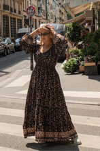Woman in a long floral boho dress standing on a city street.
