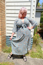 Person wearing a floral boho dress standing on a wooden deck with a garden background