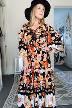 Woman wearing a floral boho dress and black hat indoors.