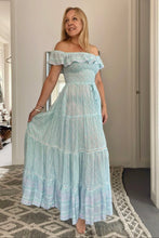 Woman wearing a light blue off-shoulder dress in a room with a neutral color scheme.