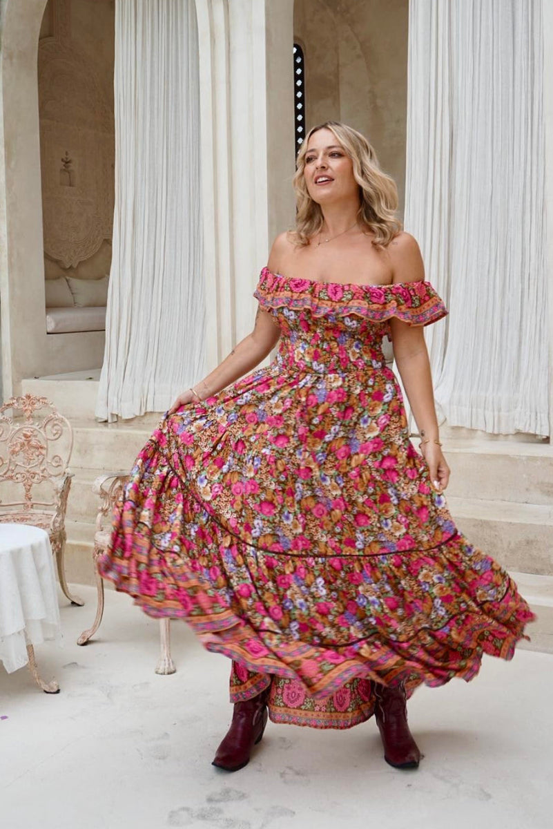 Woman in a floral off-shoulder dress standing in front of classical architecture.