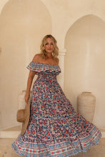 Woman wearing a floral off-shoulder dress in an arched room.