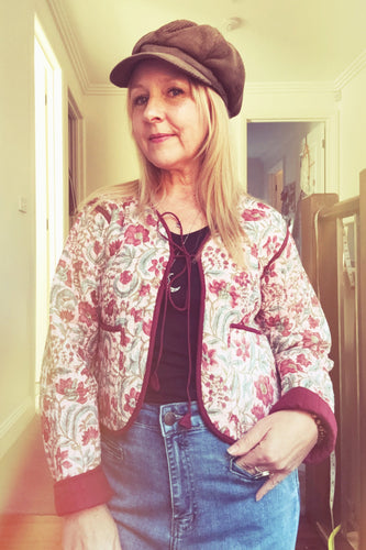 Person wearing a floral boho jacket, black shirt, and blue jeans indoors.