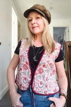 Woman wearing a boho patterned vest and cap indoors