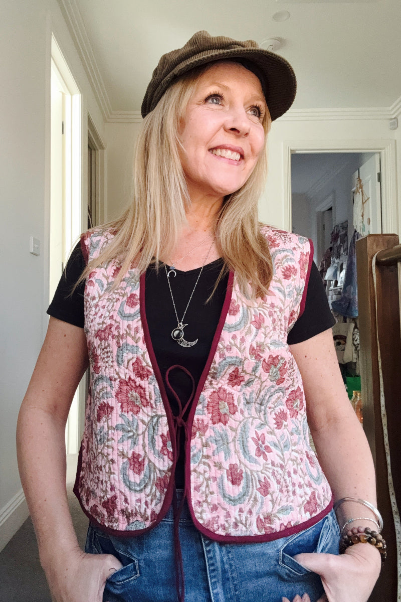 Woman wearing a boho patterned vest and cap indoors