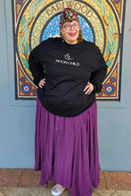 Person wearing a black 'Moon Child' boho sweatshirt and purple skirt in front of a decorative door.