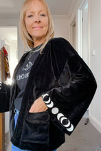 Person wearing a black jacket with white patterns indoors