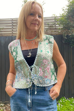 Woman wearing a boho patterned vest and blue jeans outdoors.