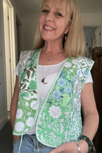 Woman wearing a green boho floral vest indoors.
