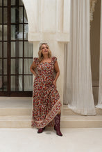 Woman in a floral dress standing in front of a building with white columns.
