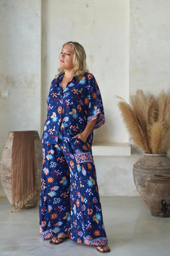 A woman modeling a boho navy blouse with tequila print, featuring square sleeves and a traditional collar, paired with matching wide-leg pants.