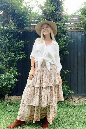 A person wearing a Eclectic Bohemian Stevie Tiered Maxiskirt in Caramel Floral. The skirt is maxi-length with three tiers and a soft elastic waistband.