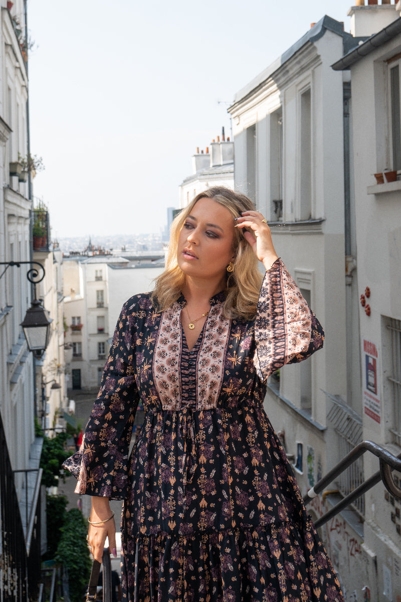 Woman in a floral boho dress standing on a city street with buildings in the background
