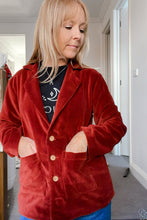 Person wearing a red velvet boho jacket in an indoor setting