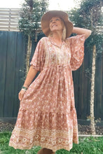 Woman wearing a floral dress and wide-brimmed hat outdoors.