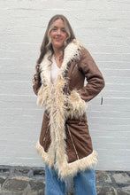 A woman wearing a brown jacket with faux fur trim, designed in a bohemian style.