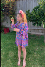 Young girl in a colorful dress playing with bubbles outdoors.